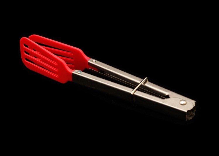A studio shot of miniature salad tongs: with metal handles secured by a square hold that slides up and down, and rubber, flat grippers at the end, like spatulas, for level grabbing.
