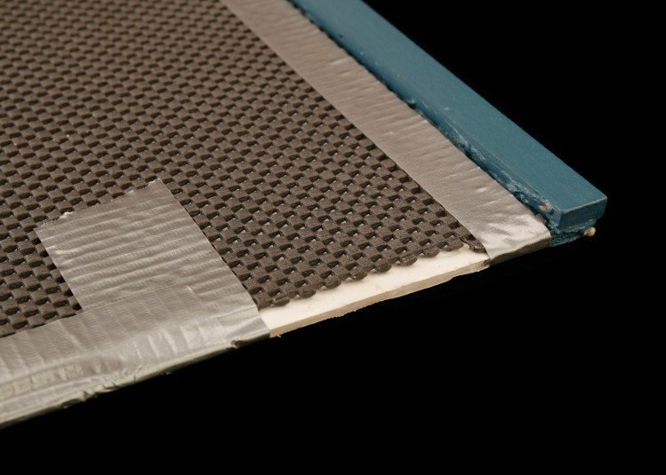 The corner of the newspaper board, with its lightweight wooden lip for stability, and its surface of foam core and shelf liner held together with duct tape.