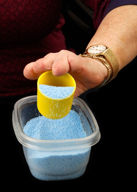 Cindy's hand can maneuver the yellow cup in this smaller-sized bin, where a standard large detergent jug would have been impossible.